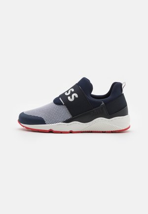 Granatowo-białe wsuwane sneakersy z siateczkową cholewką, szerokim elastycznym paskiem z napisem „BOSS”, białą śródpodeszwą i czerwoną gumową podeszwą zewnętrzną.