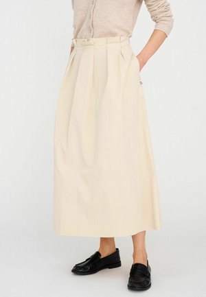 Hajtott krémszínű midi szoknya könnyű anyagból, magas derékkal és oldalzsebekkel. Fekete mokaszinekkel párosítva.