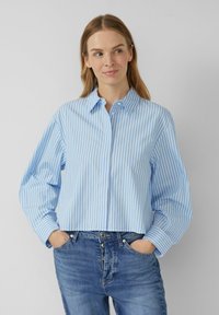 Lichtblauw overhemd met witte verticale strepen, voorzien van een klassieke kraag en lange mouwen, gecombineerd met blauwe denim jeans.