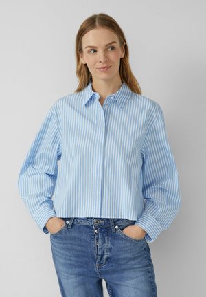 Lichtblauw overhemd met witte verticale strepen, voorzien van een klassieke kraag en lange mouwen, gecombineerd met blauwe denim jeans.