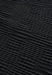 Musta teksturoitu kangas, jossa on jäsennelty, poikittain uurrettu kuvio, jossa on vaihtelevia leveysasteita, joka luo syvyyttä ja visuaalista mielenkiintoa koko pinnalle.