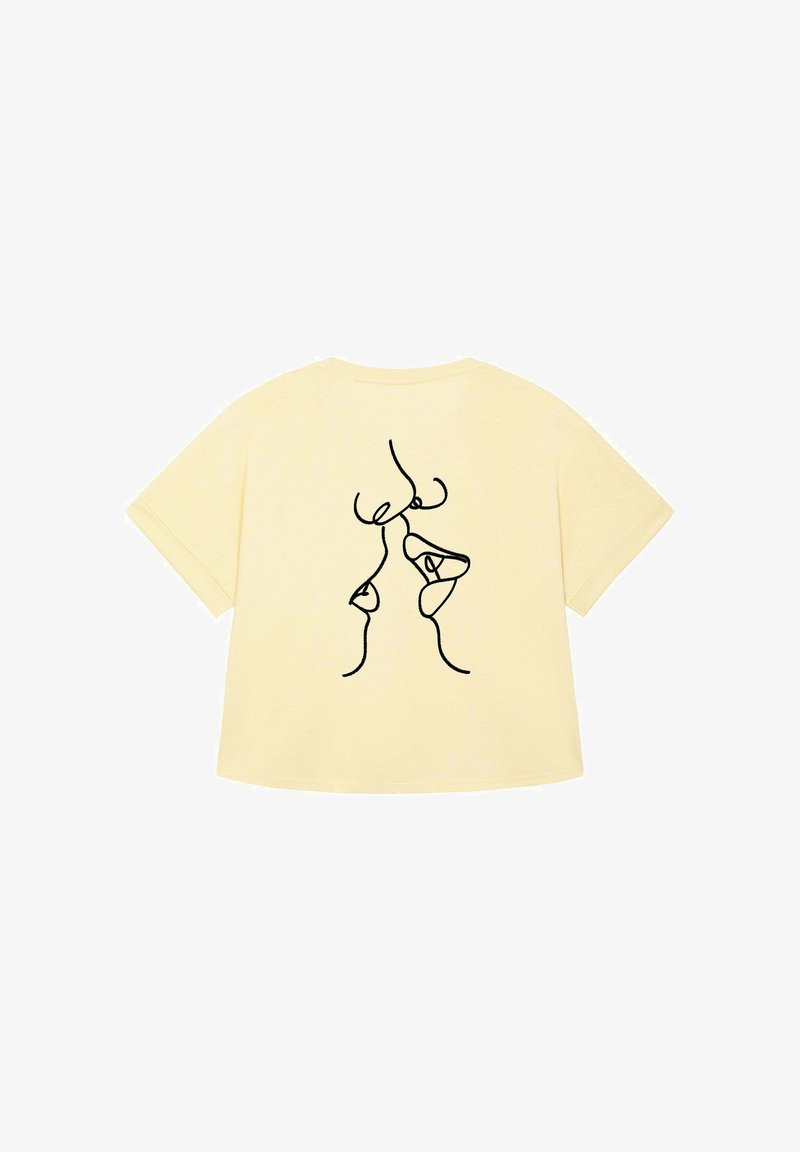 T-shirt en coton jaune avec un dessin abstrait noir au dos. Manches courtes et coupe décontractée. Texture lisse.