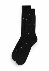 Calcetines negros hechos de una tela suave, con un patrón de pequeños puntos rojos distribuidos uniformemente por toda la superficie.