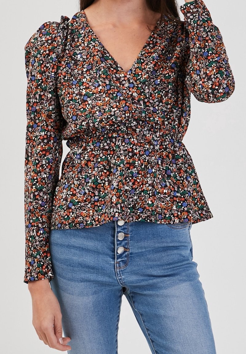Blouse fleurie avec col en V, manches longues et taille élastique. Présente des fleurs multicolores sur un fond noir. Associée à un jean taille haute.