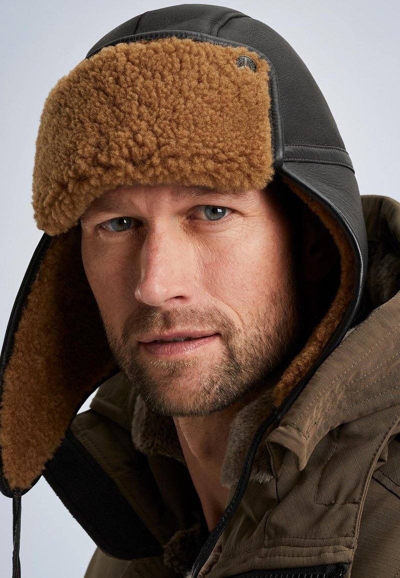 Sombrero de cuero negro con forro de borreguillo marrón y orejeras. El diseño incluye una banda frontal y cubiertas para las orejas para mayor calidez.