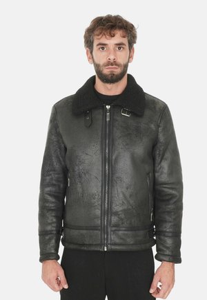 Giacca in ecopelle nera con una finitura testurizzata, dotata di un colletto in peluche nero e tasche laterali con zip. Chiusura con zip sul davanti.