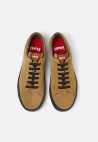 Zapatillas de ante marrón con cordones negros, suelas de goma y plantillas rojas con la marca "CAMPER". Textura suave, diseño clásico de cordones.