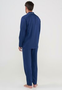 Conjunto de pijama a cuadros en azul marino con una camisa de botones de manga larga y pantalones a juego. Tela suave con ribete blanco alrededor del cuello.