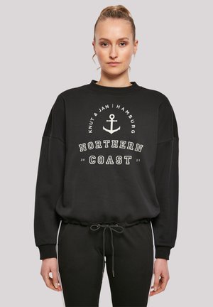Schwarzer Hoodie mit Rundhalsausschnitt, dekorativem Anker-Design und dem Schriftzug "NORTHERN COAST 2023"; kombiniert mit schwarzen Jogginghosen.