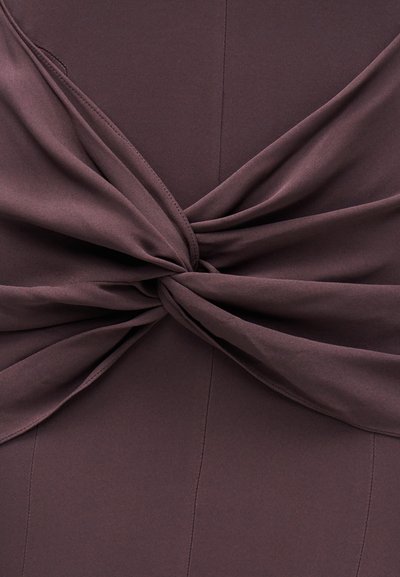 Temno vijolično tkivo, zvito v vozel detajl, ki prikazuje gladko teksturo in vidne šive na materialu.