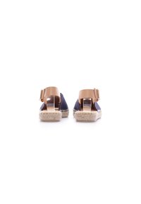 Sandalias de espadrilles con parte superior de tela en color azul marino, correa de tobillo de cuero marrón y suela envuelta en yute; diseño de parte trasera abierta con cierre de hebilla.