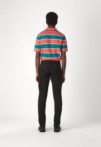 Pruhované polo tričko v korálové, tyrkysové a bílé barvě, doplněné černými cargo kalhotami. Tričko má krátké rukávy a klasický límec.