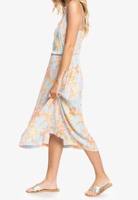 Robe midi florale avec un fond bleu et des motifs orange et rose, en tissu léger, avec des bretelles réglables et une silhouette fluide.
