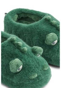 Zelene, pahuljaste papuče s dizajnom dinosaura koje imaju teksturirane detalje, zaobljen oblik, velike oči i male bodlje duž bokova.