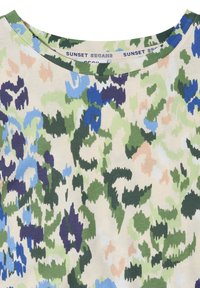Round neckline shirt with abstract camouflage pattern in green, blue, beige, and purple colors, labeled "SUNSET SHADES."