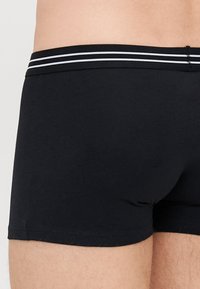 Boxer in cotone nero con una vestibilità aderente, caratterizzati da una fascia elastica nera solida decorata con due strisce orizzontali bianche.