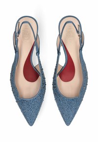 Ballerines slingback pointues bleues ornées de petits clous ronds, semelles intérieures beiges et inserts de soutien de la voûte plantaire rouges, vues de dessus.