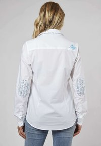 Chemise blanche à manches longues avec patch de coude à motif floral et détails brodés au col, avec poignets à boutons et ourlet arrondi.