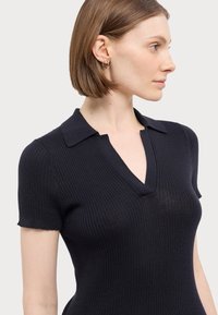 Mørkeblå ribbestrikket polo topp med korte ermer og V-hals, med en strukturert krage og subtil tekstur.
