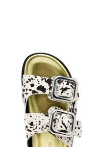 Sandali bianchi e neri a pois con due fibbie, una soletta in metallo dorato e una texture liscia. Design open-toe, suola piatta e cinturini resistenti.