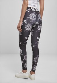 Svarta leggings med ett blommönster i grått och vitt. Tillverkade av ett mjukt, elastiskt material. Bärs med vita sneakers.