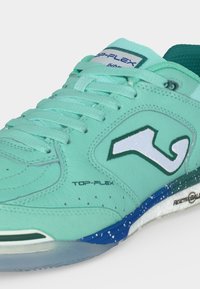 Chaussure de sport vert menthe avec lacets, logo latéral blanc et semelle bleue tachetée portant les mentions "Top-Flex" et "Reactive Ball."
