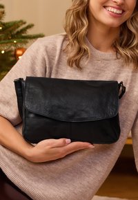 Černá kožená taška přes rameno s klopovým uzávěrem a texturovaným povrchem. Obsahuje ramenní popruh a elegantní, minimalistický design.