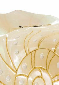 Transluzente beige Kunststoffschale mit goldenen Wirbelmustern, runden erhabenen Punkten und gewellten Rändern, ausgestattet mit einem silbernen Verschluss oben.