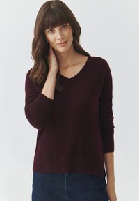 Maglione a maglia borgogna con scollo a V, maniche lunghe e vestibilità rilassata. Texture morbida con polsini e orlo a costine.
