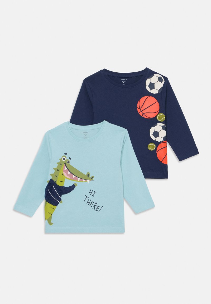 Two long-sleeve shirts: one light blue with a crocodile graphic and text, the other navy with sports ball prints in orange and white.