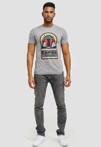 Grå bomulds t-shirt med et farverigt "Star Wars: The Empire Strikes Back" grafisk motiv af et hjelm, med rund halsudskæring og korte ærmer.