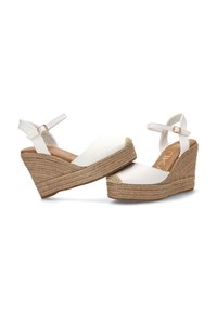 Sandalias blancas de cuña con tiras al tobillo y suelas de plataforma de yute trenzado, con punta cerrada y detalles tejidos.