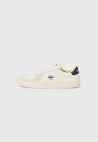 Lacoste sneakers in cream leather and suede, with a beige panel, round toe, and branding on the side and heel. Rubber sole for grip.