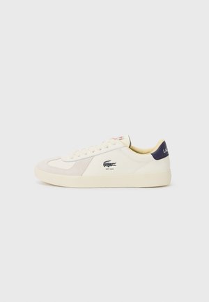 Lacoste sneakers in cream leather and suede, with a beige panel, round toe, and branding on the side and heel. Rubber sole for grip.