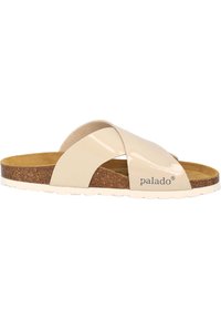 Sandalia plana de tiras cruzadas beige con parte superior sintética brillante, plantilla de corcho y suela de goma blanca texturizada. Nombre de la marca "palado" visible.