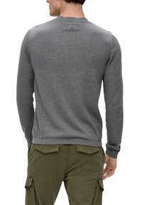 Pull gris avec un col rond et des manches longues, fabriqué en tissu doux. Conception légèrement ajustée, accompagné d'un pantalon cargo vert olive.