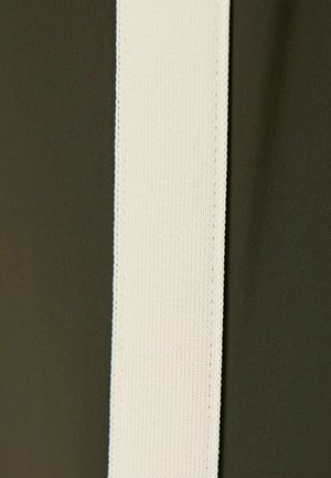 Stofstrook met een glad olijfgroen oppervlak naast een brede, geribbelde witte elastische band, met nette randen en contrasterende kleuren.