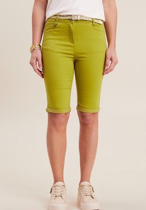 Groene katoenen bermuda shorts met opgerolde manchetten, voorzakken en een tailleband verfraaid met een gevlochten riem. Gekoerst met beige sneakers.