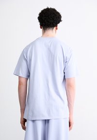 Lyseblå bomulds-t-shirt med korte ærmer, rund hals og afslappet pasform. Glat tekstur og enkelt design uden udsmykninger.
