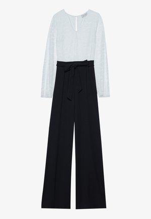 Jumpsuit mit einem hellblauen, gemusterten Oberteil mit langen Ärmeln und einem tiefen V-Ausschnitt sowie einer schwarzen, weit geschnittenen Hose mit einem Taillengürtel.