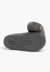 Chausson en peluche gris avec une tige douce et une semelle en caoutchouc texturé, doté d'une large sangle et d'un orteil arrondi.