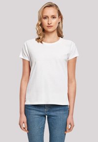 White cotton t-shirt featuring short sleeves and a round neck, with a relaxed fit and smooth texture. Worn with blue denim jeans.