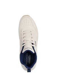 Beige sneaker with a smooth leather-like upper, navy interior, perforated toe box, and white laces. Features Skechers branding on the side.