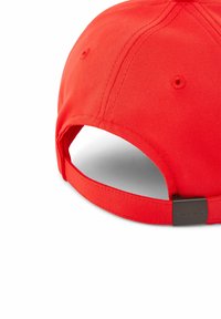 Casquette de baseball rouge en tissu lisse, avec une visière courbée, une sangle ajustable et un petit accent métallique de marque à l'arrière.