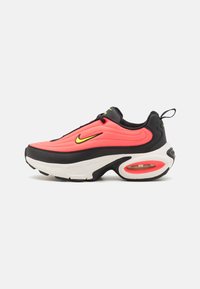 Nike sneakers with a bright pink upper, black accents, and white sole featuring visible air cushioning in the heel, textured surface, and logo.