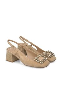 Zapatos slingback de ante beige con punta cuadrada, tacón ancho y detalle decorativo de hebilla de cristal en la parte frontal, con un acabado texturizado.