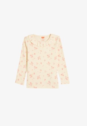 Ribbede langærmede top i lys creme med små rosa blomster; har en flæset halsudskæring og blødt, tekstureret stof.