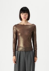 Bronze leopard-print long-sleeve top with a scalloped neckline and sheer texture, paired with gray pleated wide-leg pants.