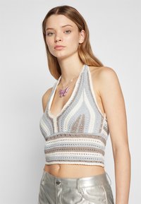 Heklet halterneck topp med et bølgete stripe-mønster i lyseblå, beige og hvit. Strukturen har en teksturert strikk med en tettsittende design og V-hals.
