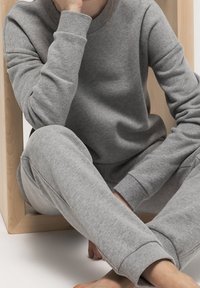 Grå sweatshirt och shorts i mjukt tyg, med ribbad mudd och avslappnad passform, tillsammans med hudfärgade bara fötter på en yta.